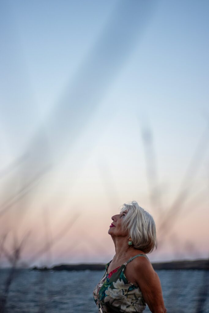 Mulher idosa olhando para o céu ao pôr do sol